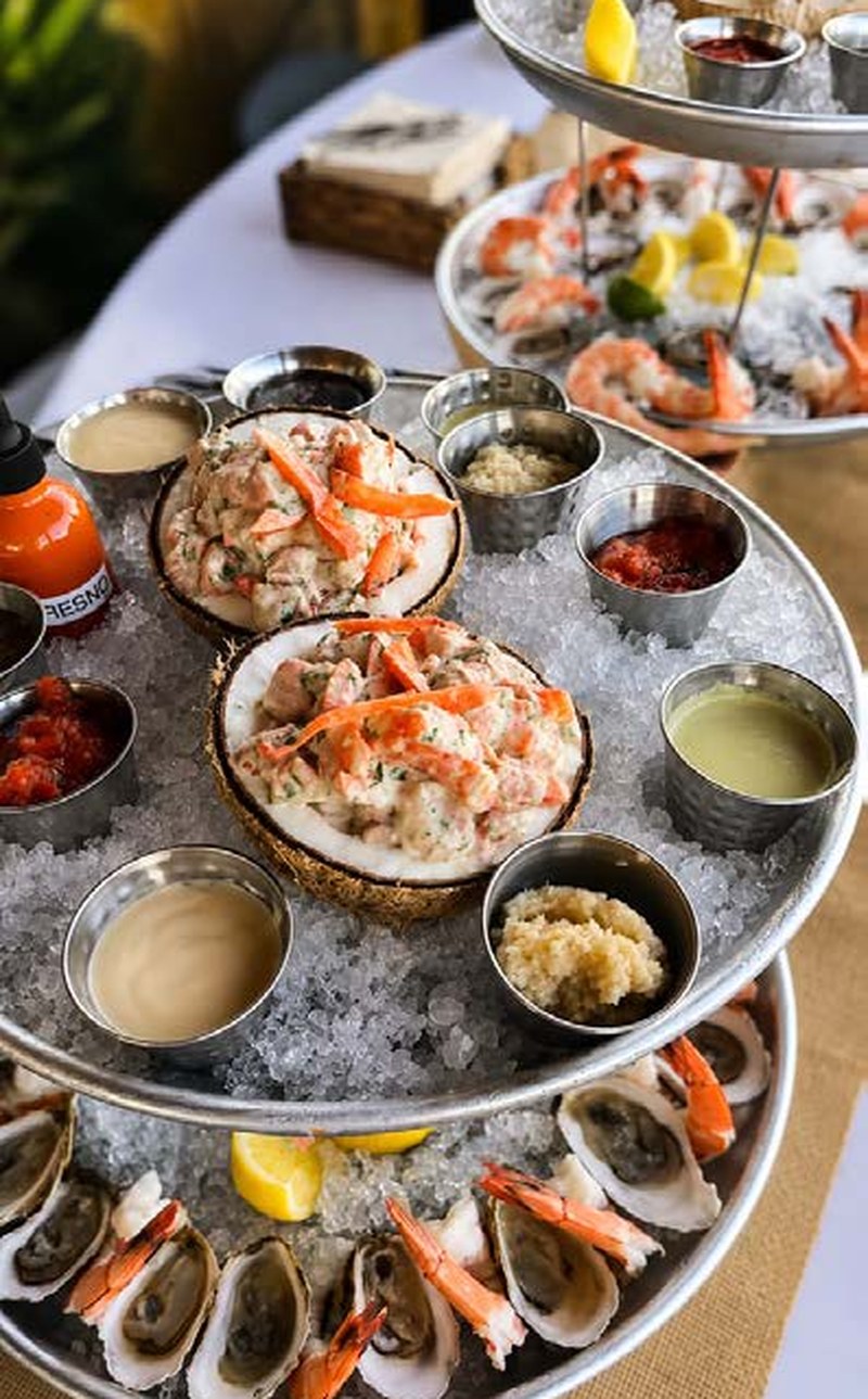 Seafood tower with raw oysters, shrimp and accompaniments on ice